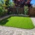 Backyard with synthetic turf and a stone patch wrapped around half of it in a curve